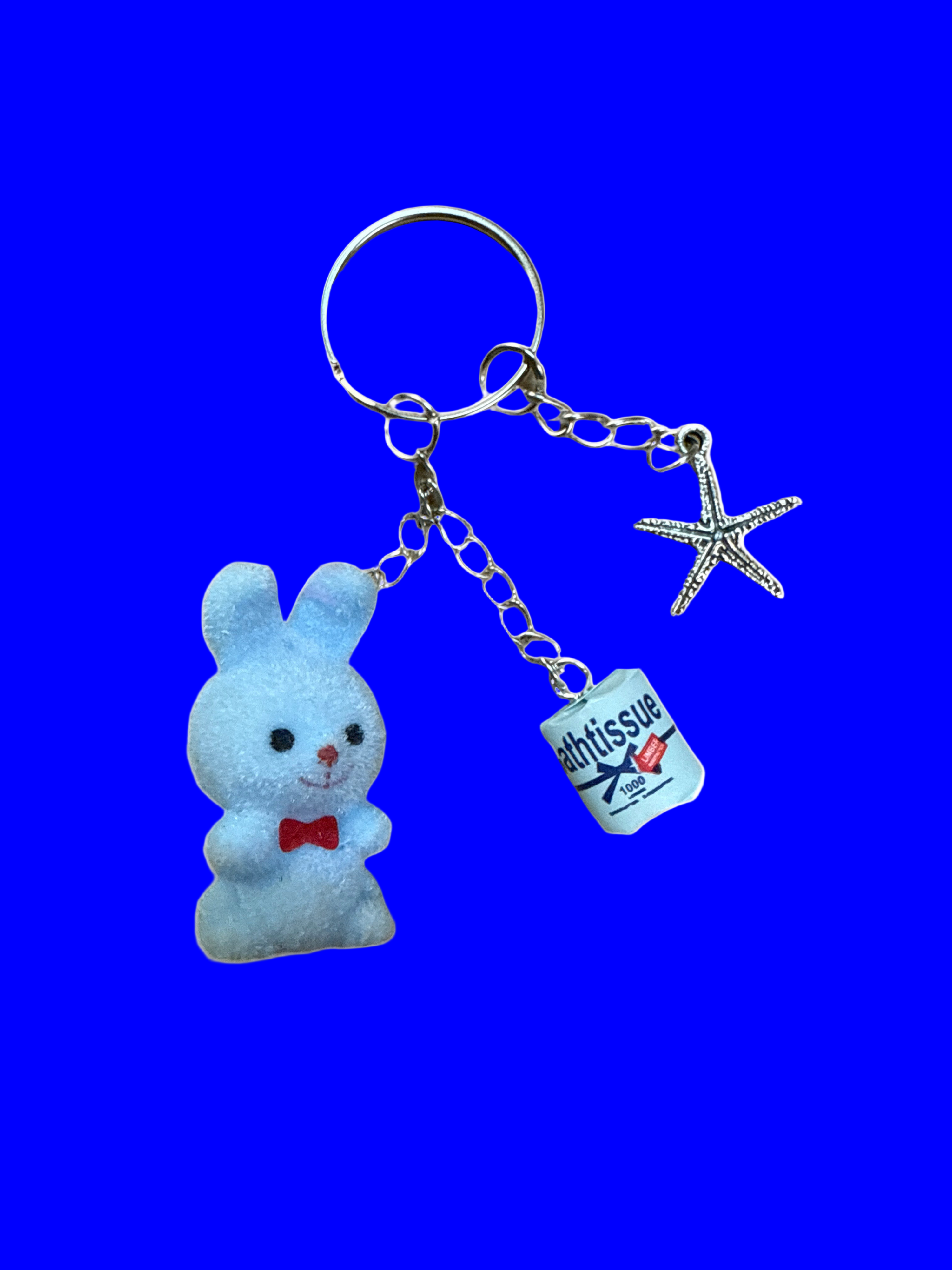 Blue plush bunny keychain with a tag and starfish charm on a blue background