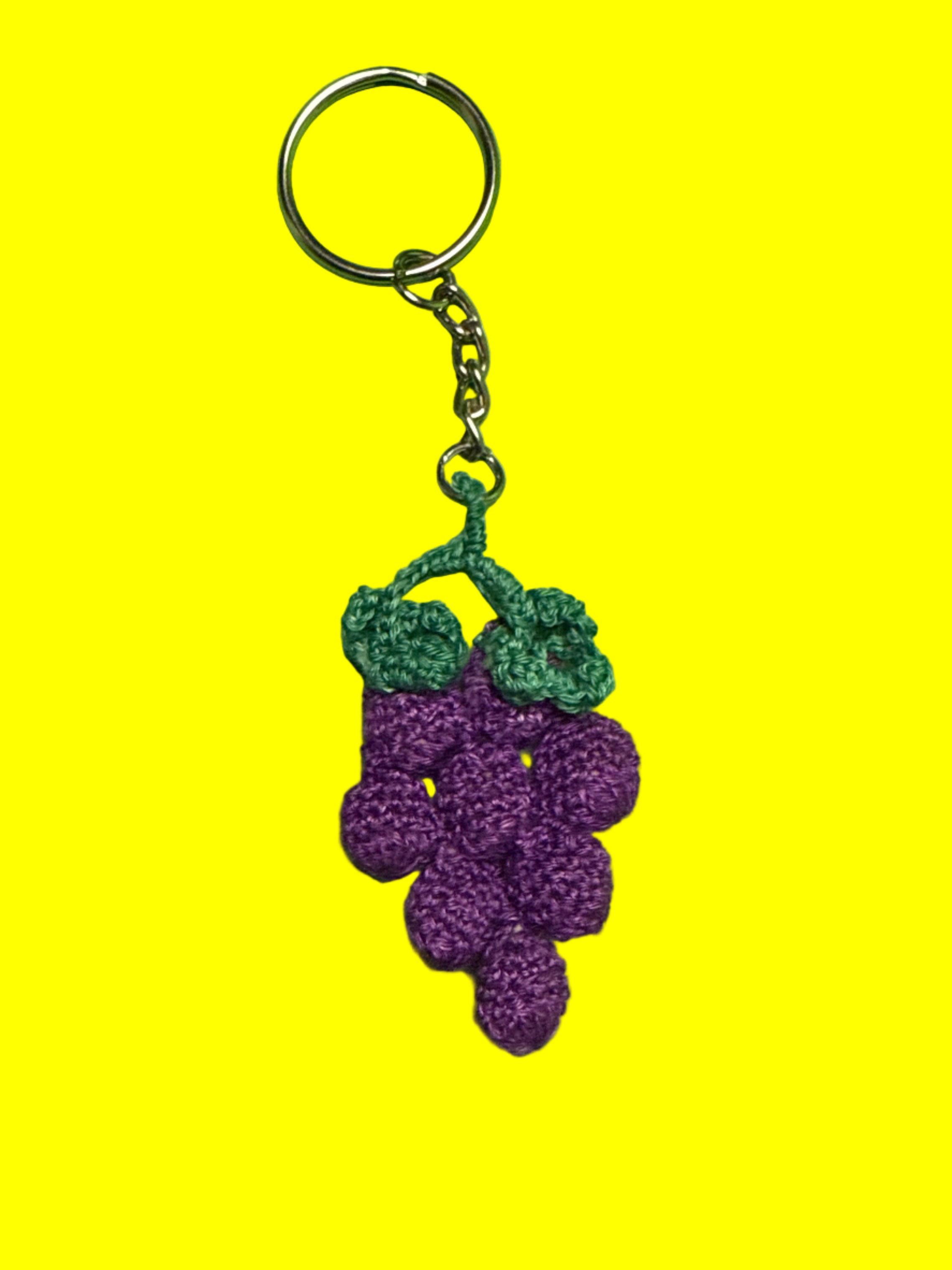 Keychain with purple and green crocheted grapes on a yellow background