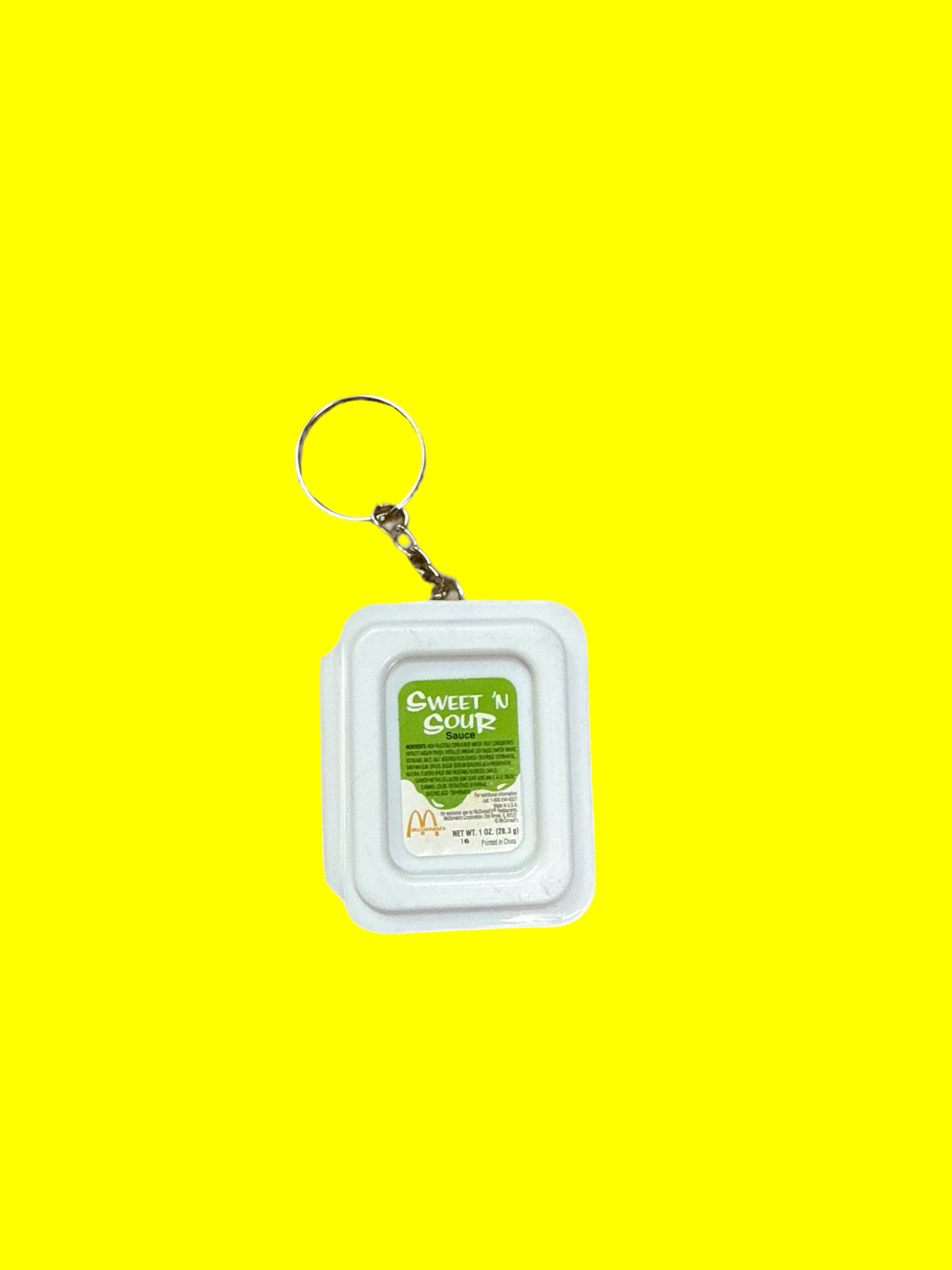 Small sweet and sour container with a keychain attached on a yellow background