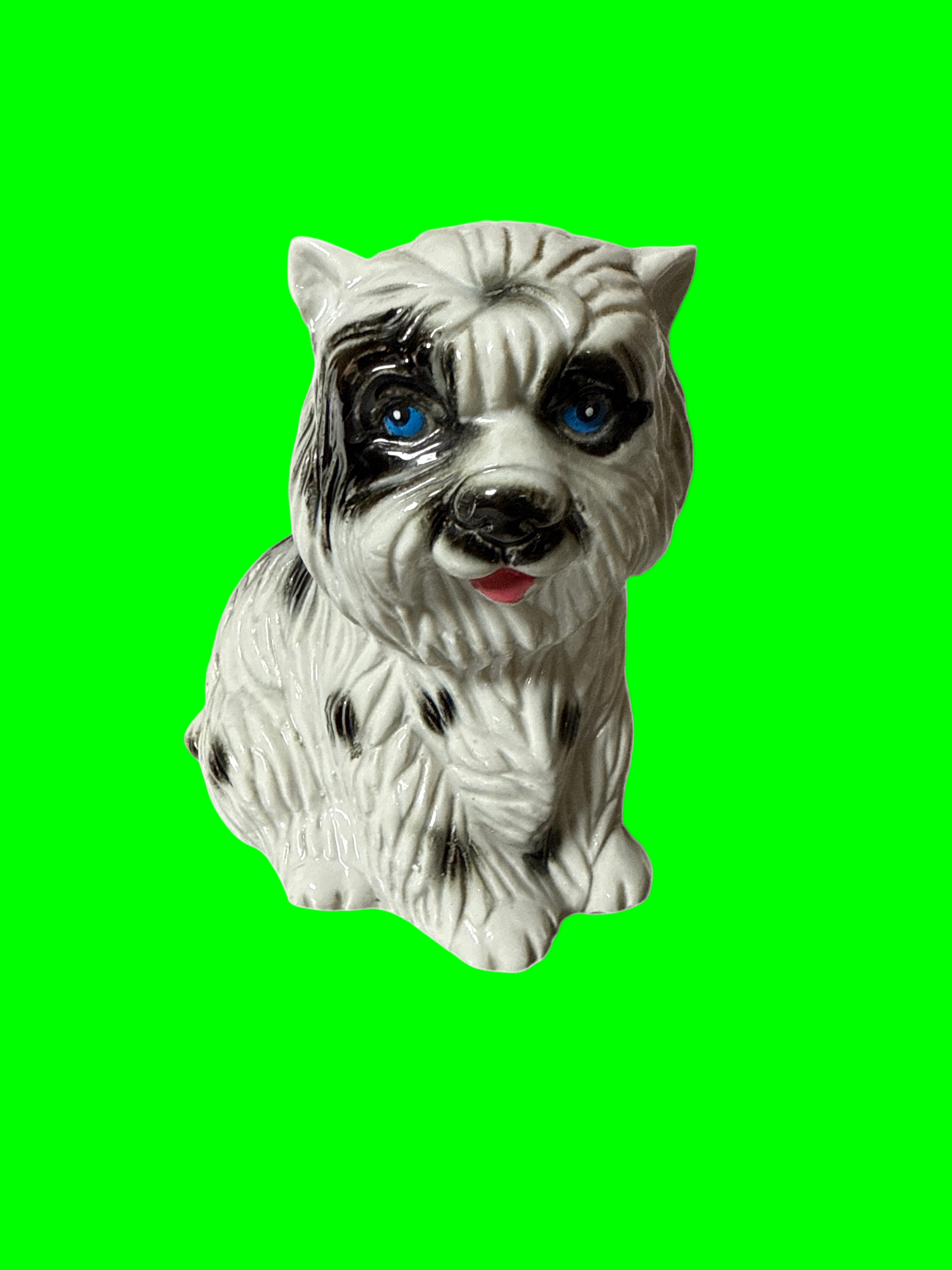 Dog figurine with a white and black pattern on a green  background
